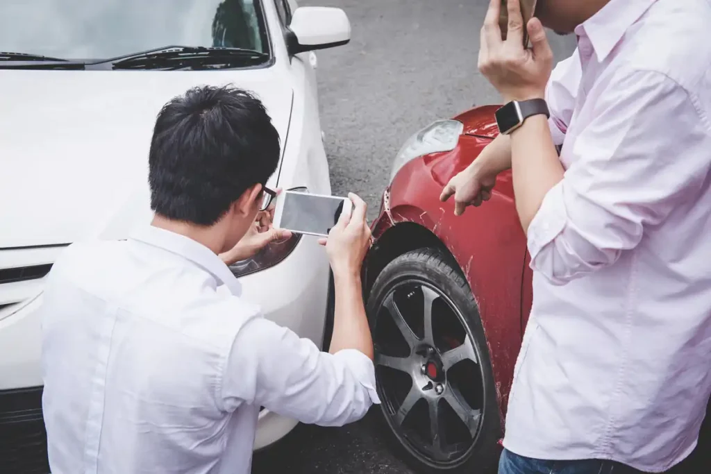 Two men documenting vehicle damage after a car accident in California, photographing the scene for an insurance claim